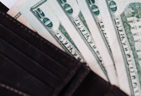 Market Opportunities - From above of black leather wallet with cash money of twenty dollars placed on white table