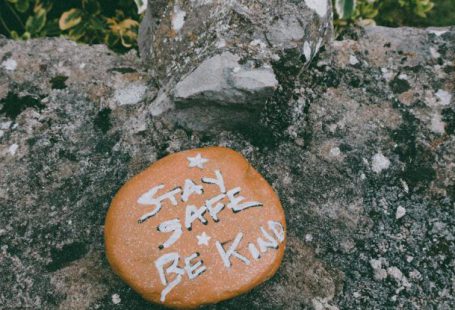 Empathy - Stay Safe Be Kind text carved on stone in green park during coronavirus pandemic