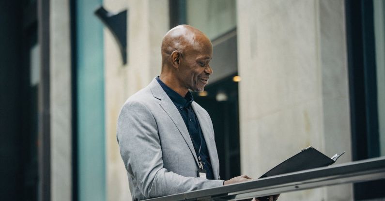 Board Of Directors - Cheerful African American manager reading documents in folder