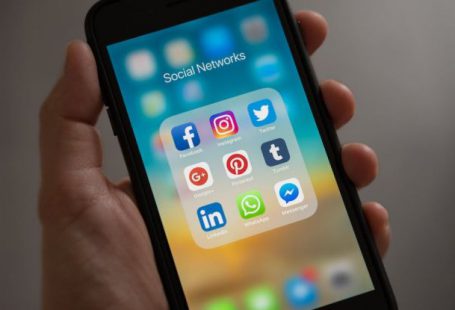 Social Media Marketing - Person Holding Iphone Showing Social Networks Folder