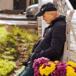 Solution Selling - A man sitting on a bench with flowers in his hand