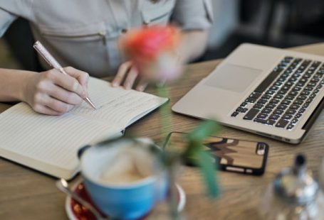 Content Marketing - Person Writing On A Notebook Beside Macbook